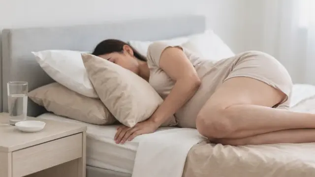 Schwangere in Seitenlage mit Kissen im Bett als Hilfe gegen Reflux in der Schwangerschaft