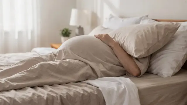 Schwangere in Seitenlage im Bett als Schlafposition im ersten Trimester